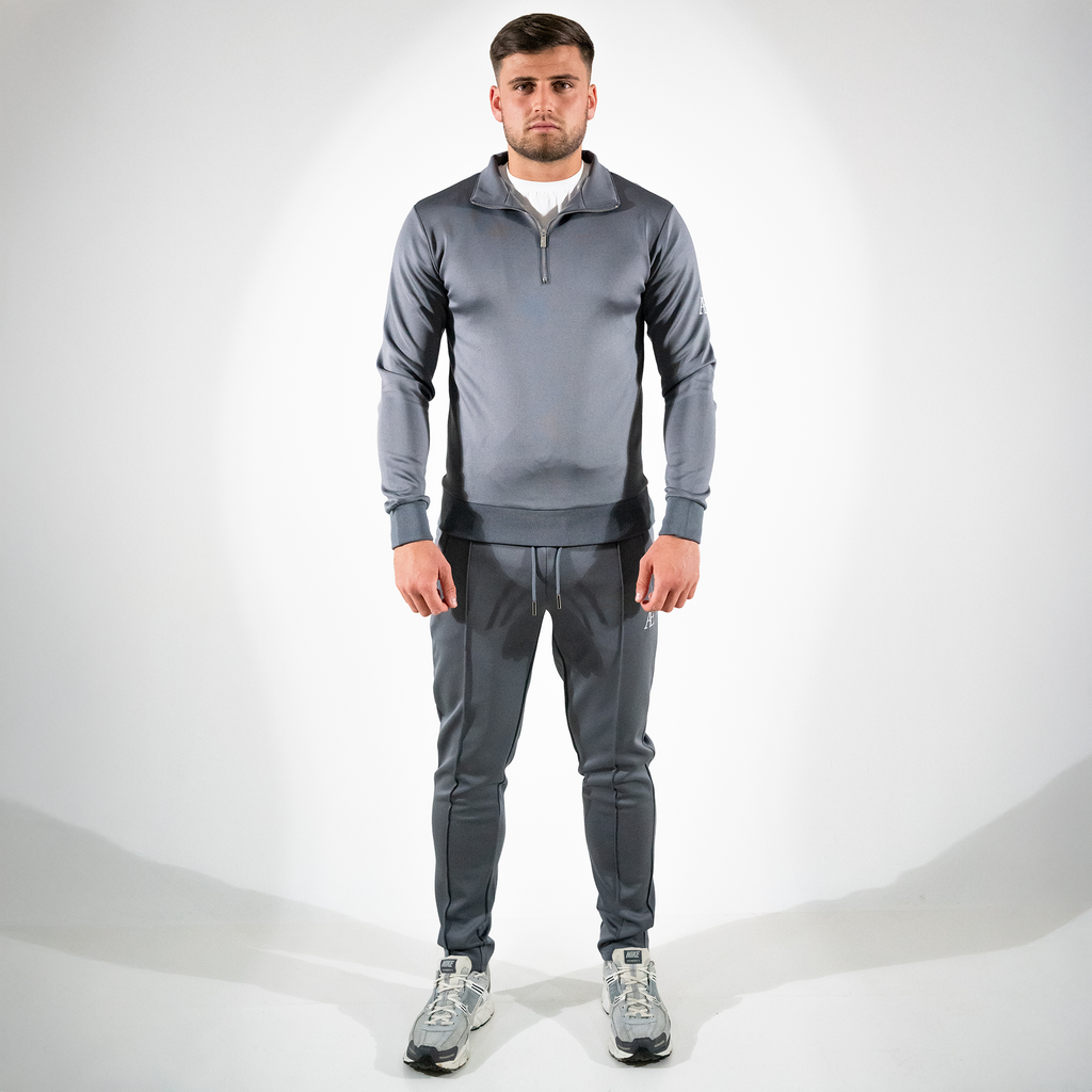 Model in gray slim-fit bottoms and matching quarter-zip, minimal AÉCLO branding
