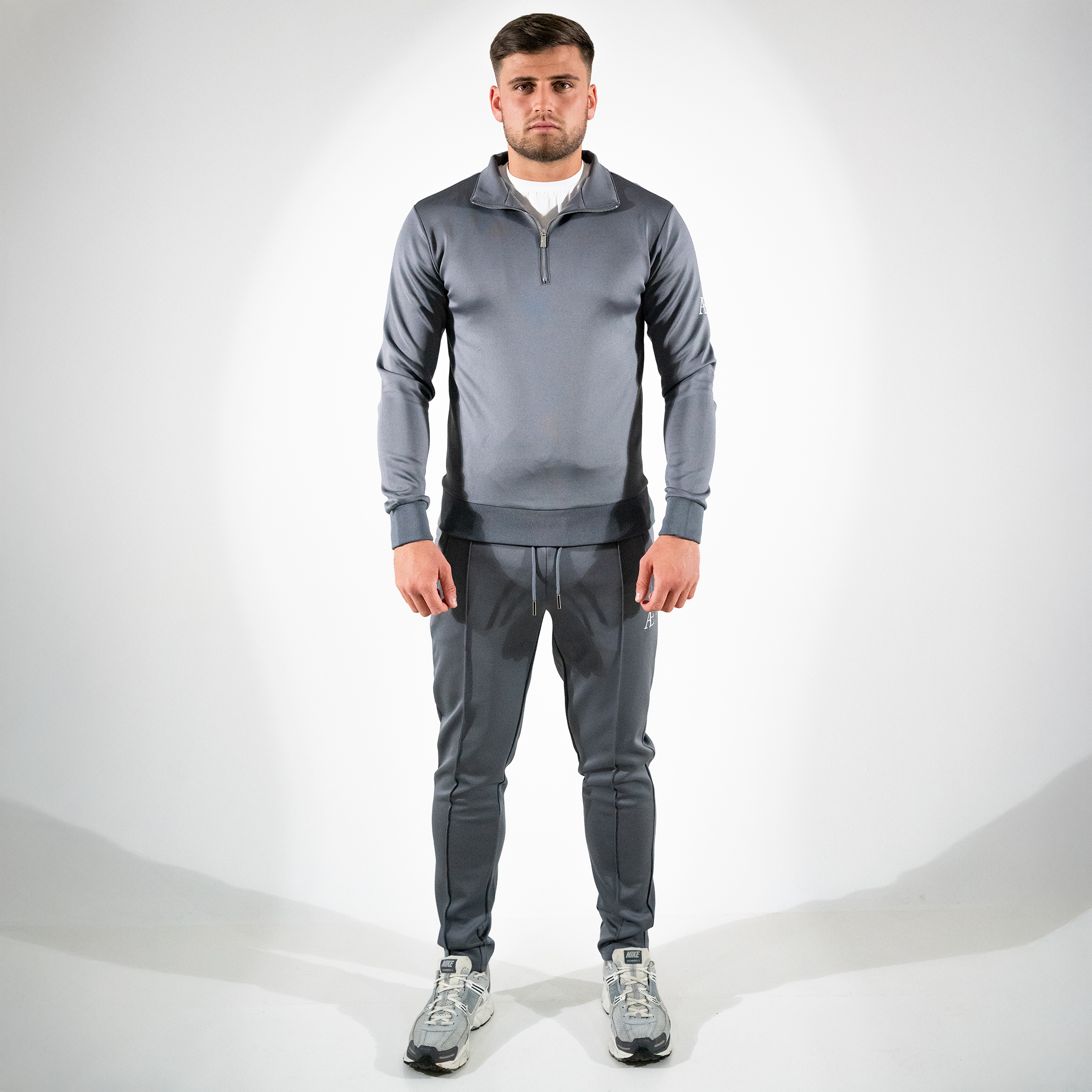 Model in gray slim-fit bottoms and matching quarter-zip, minimal AÉCLO branding
