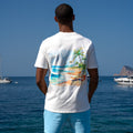 Man wearing relaxed-fit white tee with colorful beach graphic on back by the ocean